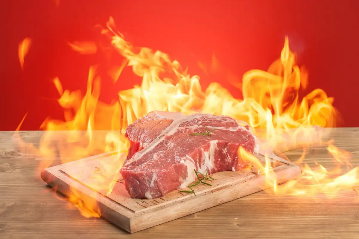 Svež T-bone zrezek na deski med plameni